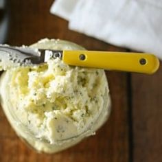 a jar filled with mashed potatoes sitting on top of a wooden table next to a knife