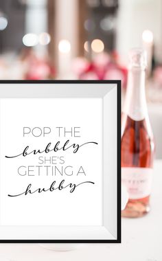 a bottle of wine sitting next to a framed sign that says pop the bubbles she's getting a juice