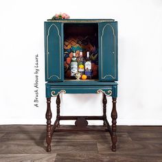 an old fashioned cabinet with drinks in it on top of a wooden floor next to a white wall