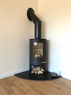 a black stove sitting on top of a hard wood floor next to a white wall