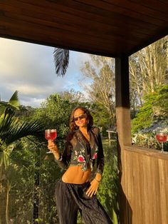 a woman standing on a porch holding a glass of wine