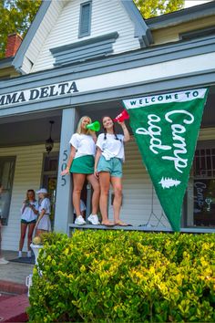 two girls standing on top of a green flag in front of a building with people walking by