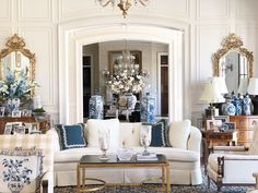 a living room filled with white furniture and lots of blue and white decor on the walls