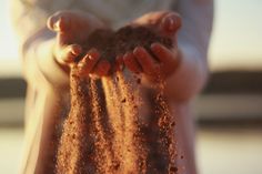 a person holding sand in their hands