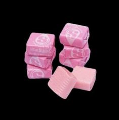 pink candy cubes stacked on top of each other in front of a black background