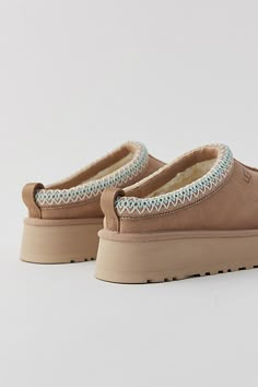 A maximalist take on the timeless Tasman, the Tazz refreshes the familiar silhouette with a platform sole for boosted cushioning and style. Crafted from the same rich suede as the original, it's lined in signature UGGplush™ wool blend for a slipper-like feel indoors or out. UGG® Tasman braid (70% recycled polyester, 30% rayon) and heat-embossed logo. Content + Care Suede, UGGplush™ (80% upcycled wool, 20% Lyocell), EVA Spot clean Imported Size + Fit True to size Platform height: 1.5" | UGG Tazz Slipper in Sand, Women's at Urban Outfitters Uggs Platform Boots, Shoes Slip On, Tan Shoes Women, Ugg Tasman Slippers Platform, Tasman Uggs Platform, Uggs Tasman Platform, Shoes For The Fall, Cute Shoes For Winter, Girl Stuff To Buy