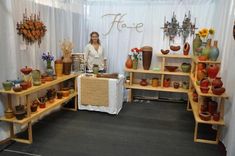 a woman standing in front of a display of vases and other items on shelves