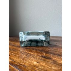 an empty glass block sitting on top of a wooden table next to a white wall