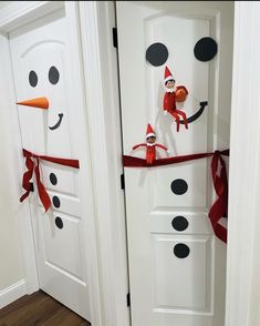 two doors decorated to look like snowmen with faces and noses on them, tied in red ribbon