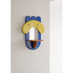 a blue and yellow animal shaped mirror mounted to the side of a wall next to a white door