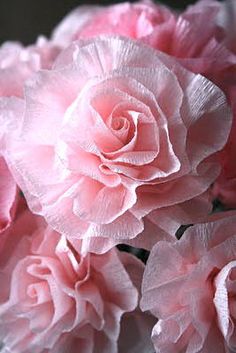 some pink flowers are in a vase on the table and it looks like they have been made out of tissue paper