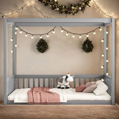 a child's bed with christmas lights on the wall and a cow stuffed animal