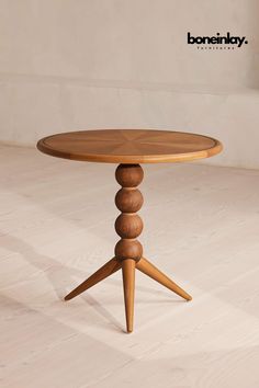 a round wooden table with three legs on white wood flooring and walls in the background