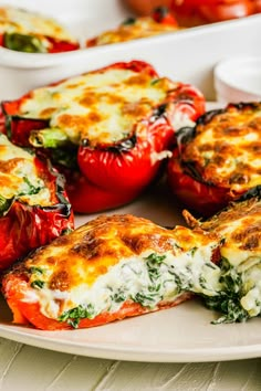 several stuffed peppers on a white plate with other dishes in the backgroung