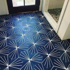 a bathroom with blue and white flooring next to a window in the shower area