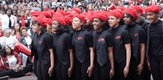 a group of women wearing red hats standing next to each other in front of a crowd