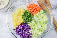 chopped vegetables in a glass bowl with a wooden spoon on a marble counter top next to a knife