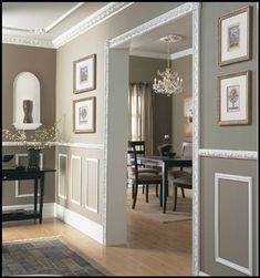 a living room filled with furniture and framed pictures on the wall next to a table