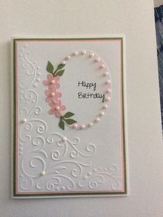 a birthday card with flowers and pearls on the front, in white paper that says happy birthday