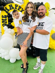 a man and woman standing next to each other in front of a balloon arch with the words happy on it