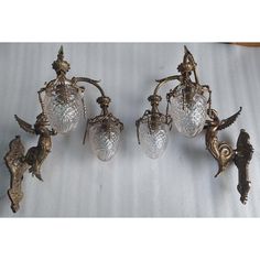 three antique brass wall lights with glass shades on the arms and two cherubs attached to them