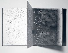 an open book with water droplets on the cover and inside pages, in black and white