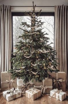 a christmas tree with presents under it in front of a window