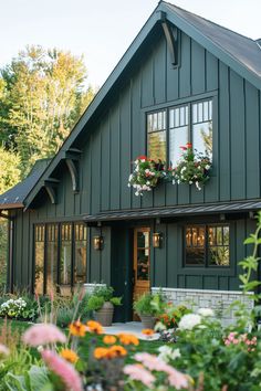 a green house with lots of flowers in the front yard and windows on each side