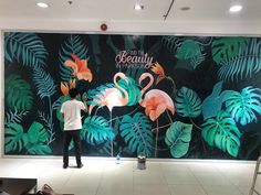 two men are standing in front of a wall mural with flamingos and tropical leaves