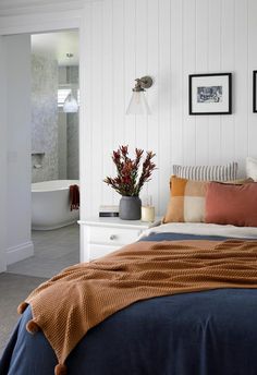 a bedroom with a bed, dresser and pictures on the wall above it that is decorated in orange and blue