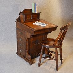 an antique desk and chair with books on it