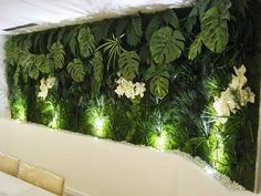 a living wall with white flowers and green plants on it's sides, surrounded by greenery