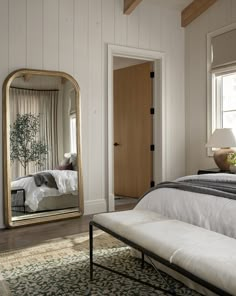 a bedroom with a large mirror on the wall and a bench in front of it