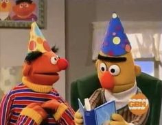 the sesame character is reading a book to another person in a clown hat and striped shirt