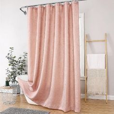 a pink shower curtain in a bathroom next to a white bath tub and wooden floors