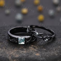 two wedding rings sitting on top of each other with an emerald stone in the middle