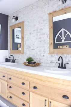 a bathroom with double sinks and two mirrors on the wall above them is decorated in black and white