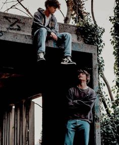 two young men sitting on top of a cement structure