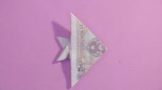 an origami bird made out of money on a pink wall with purple background