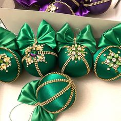 six green christmas ornaments with bows in a box