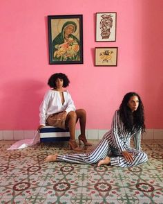 two women sitting on the floor in front of pink walls