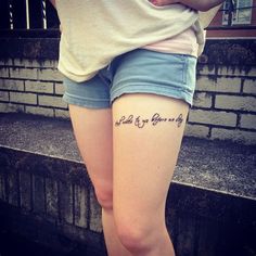 a woman with a tattoo on her thigh standing in front of a brick wall and stairs