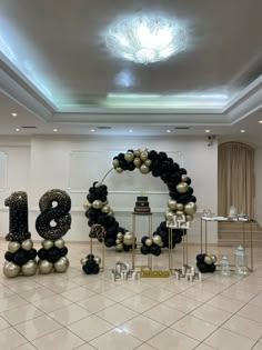 a large number decorated with black and gold balloons in the middle of a floored room