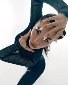 a woman is posing with her hands on her head and wearing black leather clothing,