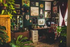 a room filled with lots of plants and pictures on the wall next to a desk