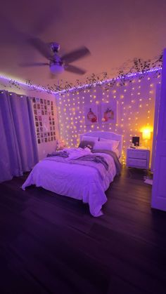 a bedroom decorated in purple and white with fairy lights