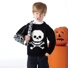 a young boy wearing a sweater with a skull and crossbones on it