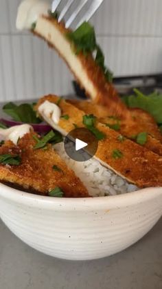 a white bowl filled with rice and fish on top of a counter next to a fork