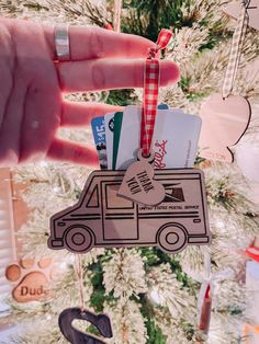 a hand holding up a christmas ornament with a car on it's side