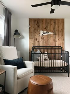 a baby's room with a black crib, white chair and brown ottoman